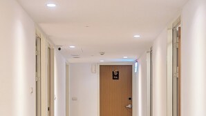A long, narrow hallway with carpeted floors and white walls. - Yen Inn (New Taipei City)