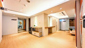 A modern hotel lobby with a wooden floor, a reception desk, and directional signs to rooms R12-R13 and R14-R18. - Yen Inn (New Taipei City)