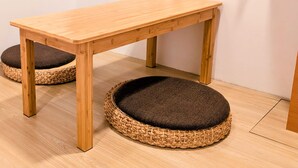 A wooden table with a woven basket floor mat. - Yen Inn (New Taipei City)