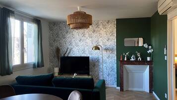 A living room with a sofa, TV, and a dining area.