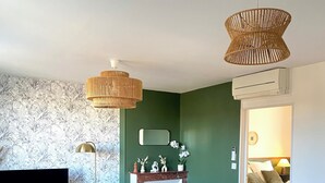 Una sala de estar con una pared verde, chimenea, televisor, sofá y mesa de comedor con sillas.