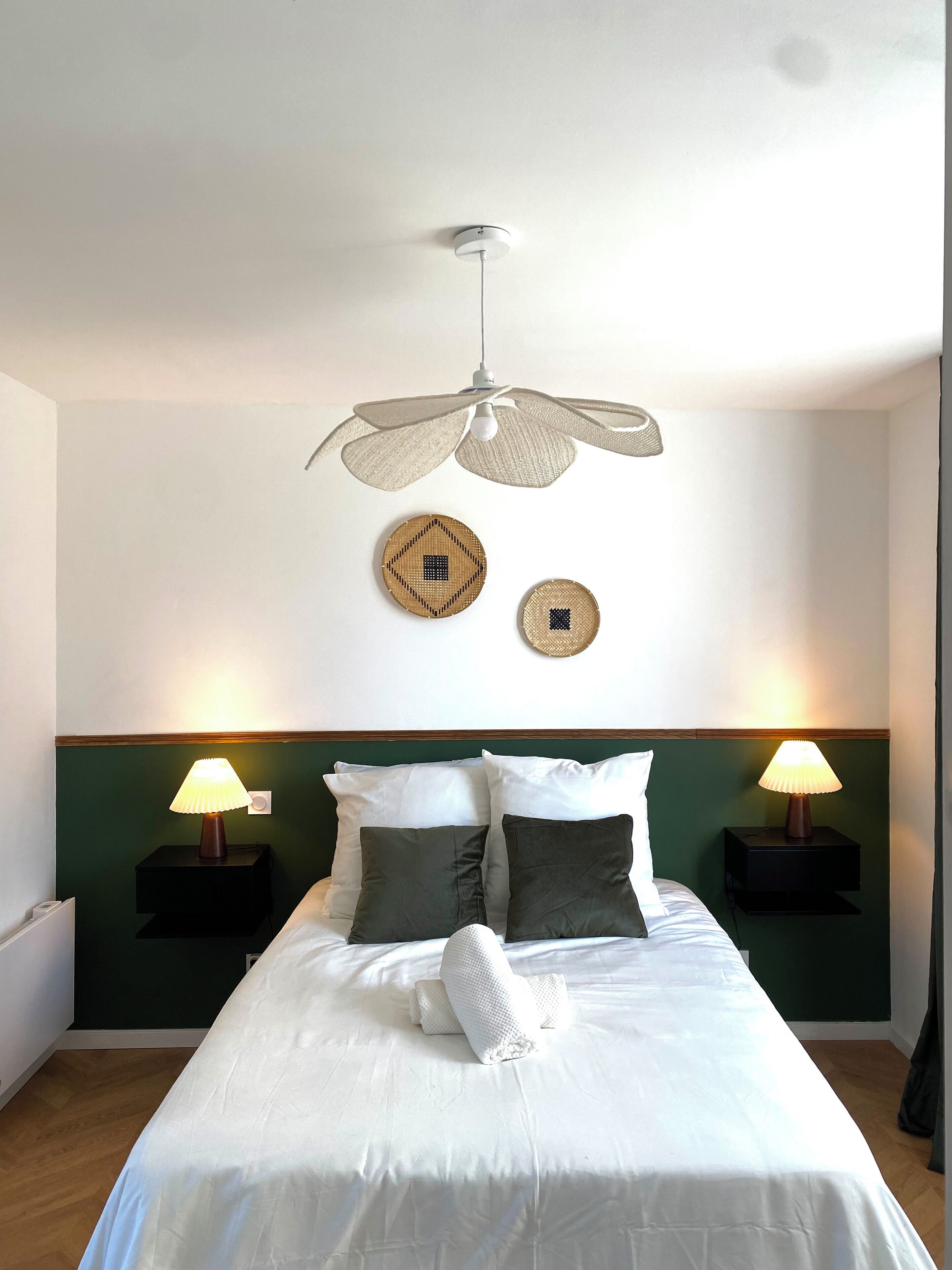 A neatly made bed with white linens, two bedside lamps, and a ceiling fan.