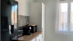 Una cocina moderna con un refrigerador negro, una máquina de café y una encimera de madera.
