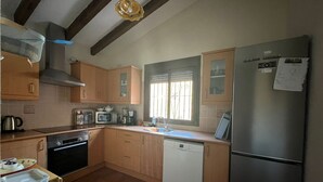Eine kleine Küche mit Holzschränken, einem Edelstahl-Kühlschrank, einer Spülmaschine und einer Mikrowelle.