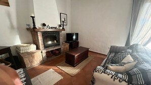 Ein Wohnzimmer mit Kamin, einer Couch, einem Couchtisch und einem Fernseher.
