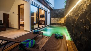 A modern outdoor pool area with lounge chairs and a stone wall. - 3Bedroom - 703 - Private Pool Villa Sanur (Denpasar Selatan)