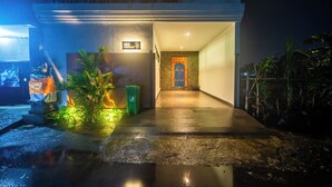 A nighttime entrance to a building with a wet ground, a green trash bin, and a sign indicating room number 703. - 3Bedroom - 703 - Private Pool Villa Sanur (Denpasar Selatan)
