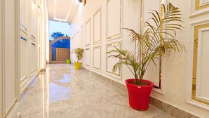 A hallway with marble floors, potted plants, and decorative moldings. - Asapin Vanymahal (Kaladhungi)