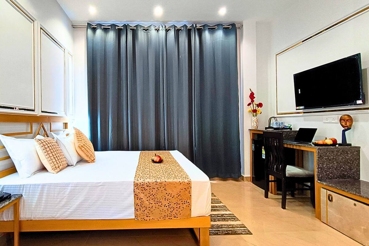Ein Hotelzimmer mit Bett, Nachttisch, Schreibtisch und Fernseher.