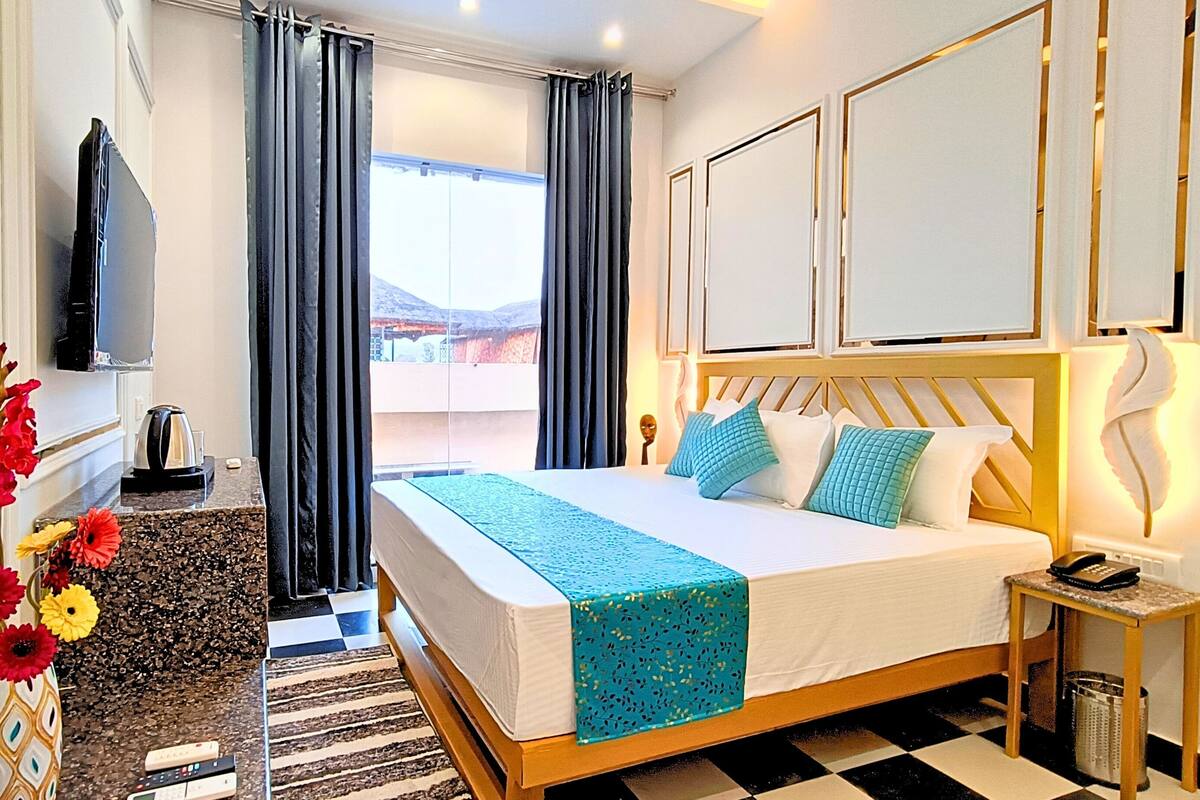 Ein Hotelzimmer mit Bett, Fernseher, Schreibtisch mit Wasserkocher und Blick ins Freie.