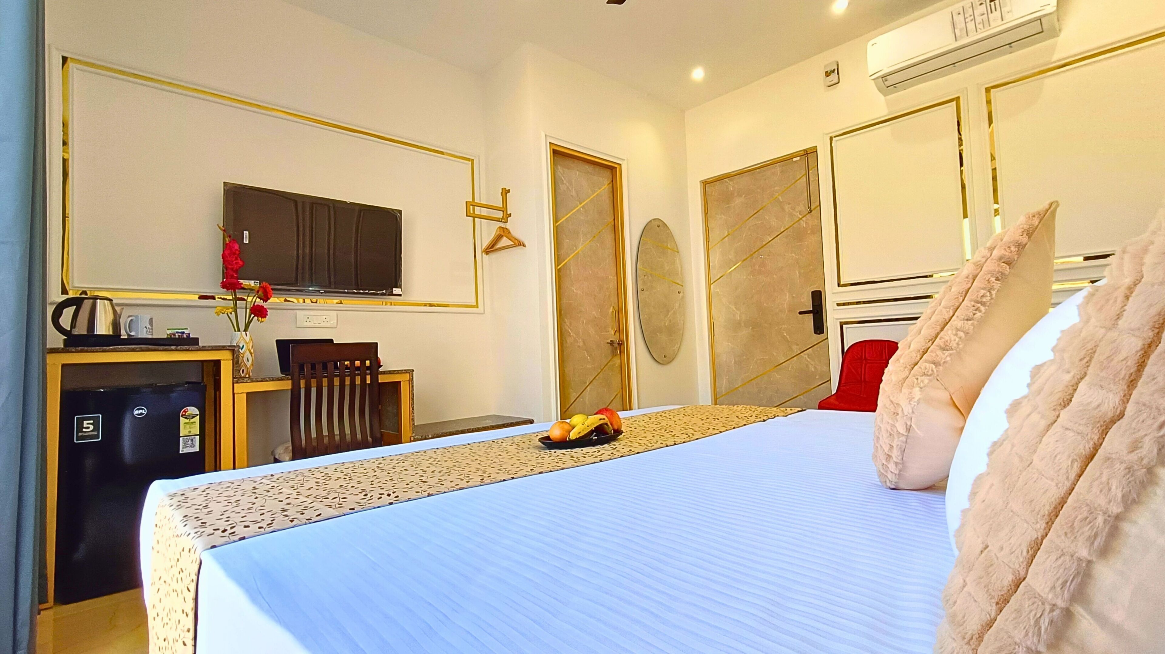 Habitación de hotel con cama, escritorio, computadora, televisor y minibar.