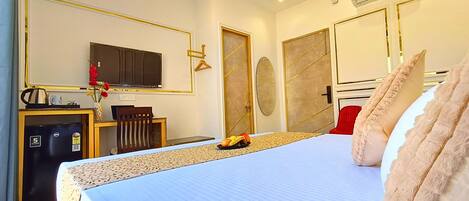 Habitación de hotel con cama, escritorio, computadora, televisor y minibar.