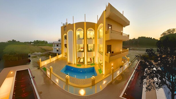 A modern multi-story hotel with a swimming pool and outdoor lighting. - Asapin Vanymahal (Kaladhungi)