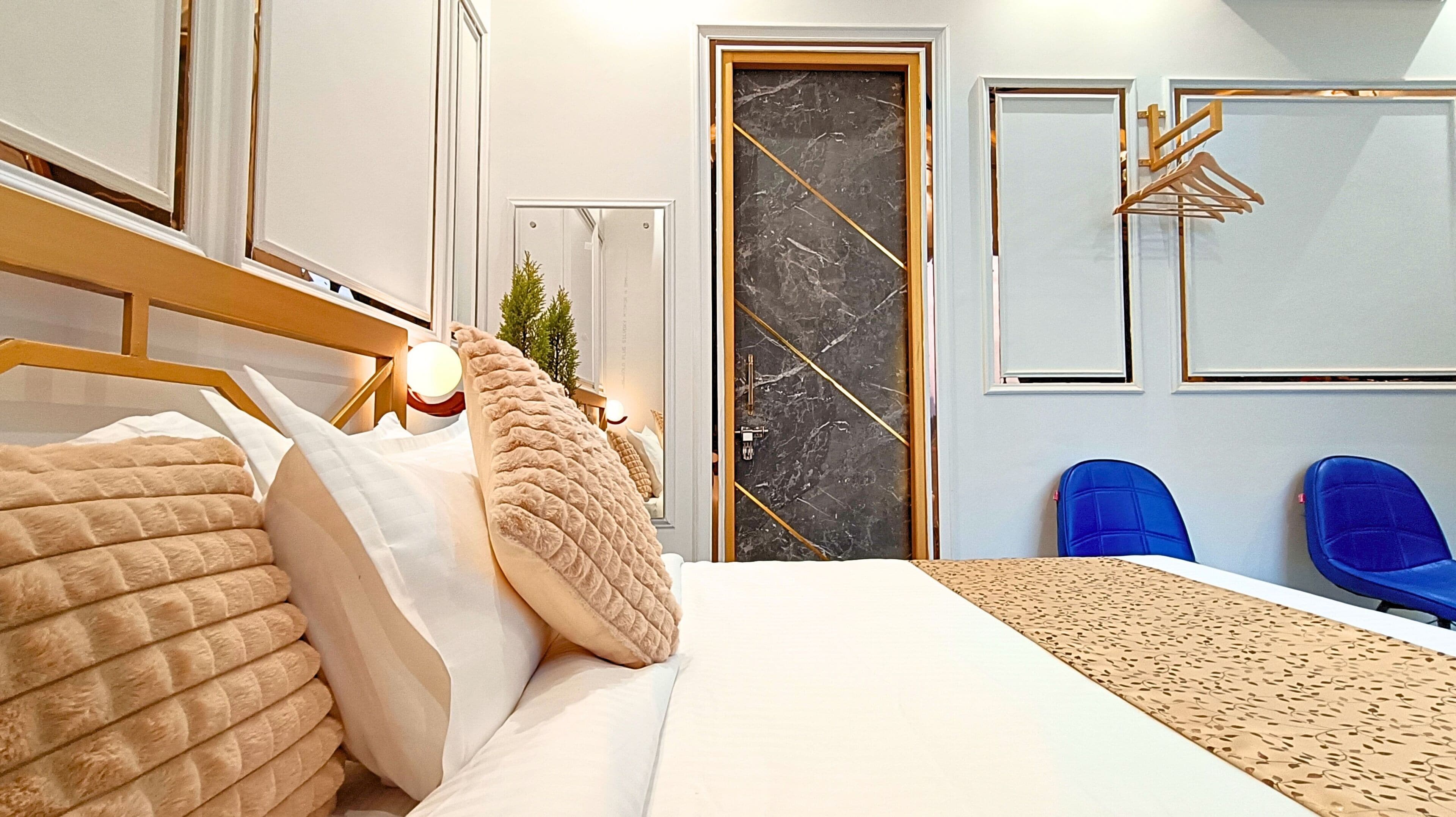 A bedroom with a bed, a nightstand, a dresser, a mirror, a door, and a blue chair.