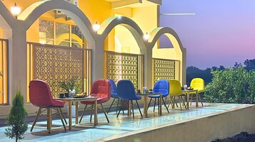 An outdoor seating area with multiple chairs and tables, a decorative fence, and a pool.