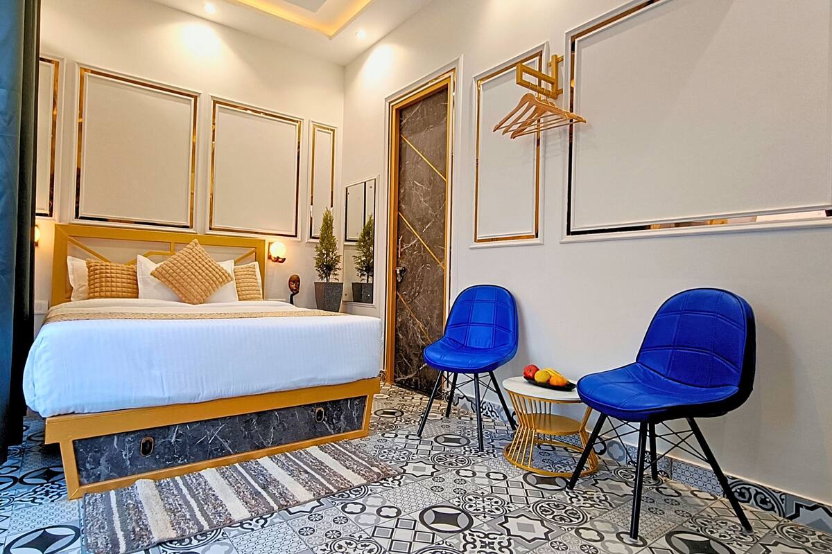 Ein Schlafzimmer mit einem Bett, zwei blauen Stühlen, einem Marmorboden und einem großen Spiegel.