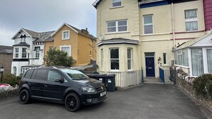 A residential street with houses, a parked car, and a blue door.