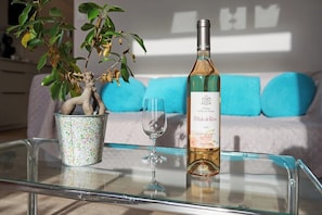 A bottle of wine, a glass, and a potted plant on a glass table.