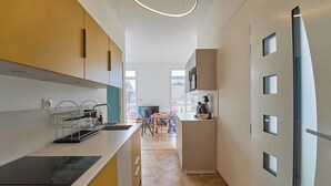 A modern kitchen with a central island, a dining area with a table and chairs, and a view of the outside.