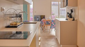 A kitchen with a dining area, a coffee machine, and a view of the outside.