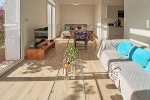 A modern living room with a sofa, a dining table, a TV, and a kitchen area. - A Cozy Family Paradise with a Terrace & Plenty of Natural Light (Toulon)