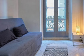 A room with a grey sofa, patterned rug, and a door with decorative glass panels.
