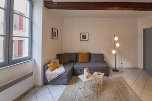 En stue med en grå sofa, et lille sofabord, en gulvlampe og en radiator.