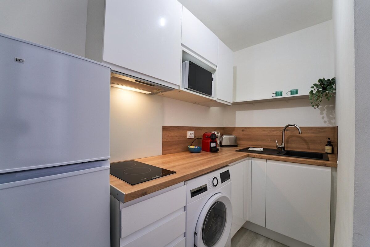 Een kleine keuken met een inbouw wasmachine, een magnetron en een spoelbak.