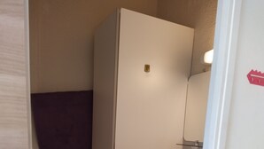 Un baño pequeño y funcional con inodoro blanco, lavamanos y espejo. Hay una toalla colgada en la pared y un calentador pequeño fijado a la pared.
