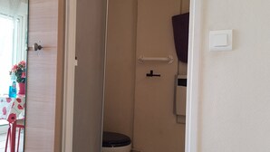 Baño con ducha, inodoro y barandilla.
