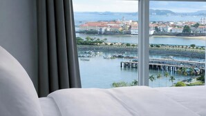 A hotel room with a large bed, a view of a marina, and a cityscape with buildings and a bridge. - 80m² Luxury Ocean View Apartment PH The Sands, Next to Hilton (Panama City)