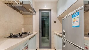 A modern kitchen with stainless steel appliances, a built-in oven, and a refrigerator. - Uhome Apartments (Shenzhen)