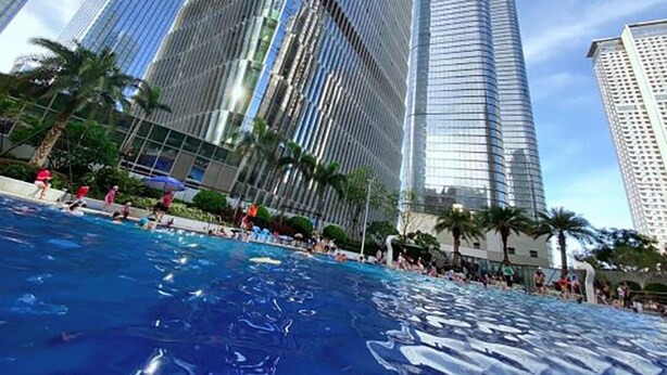 A swimming pool with people around it, surrounded by tall buildings. - Uhome Apartments (Shenzhen)