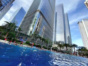 Una piscina con gente alrededor, rodeada de edificios altos.
