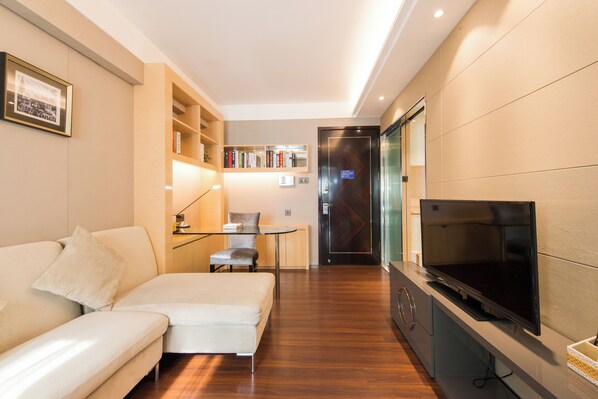 Una sala moderna con sofá, televisor, estantería y comedor.