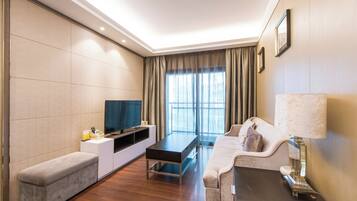 Habitación de hotel moderna con televisor de pantalla plana, sofá, banco y lámpara.