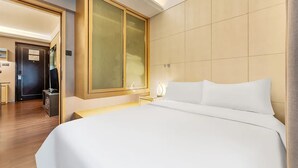 A hotel room with a large bed, a wooden wardrobe, a desk, and a mirror. - Uhome Apartments (Shenzhen)