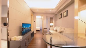A modern hotel room with a flat-screen TV, a glass coffee table, a sofa, and a bed. - Uhome Apartments (Shenzhen)