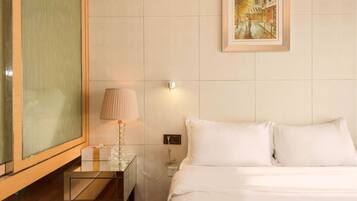 Una habitación de hotel con una cama, una mesita de noche con lámpara, un cuadro en la pared y un ventanal grande.