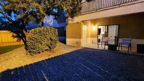 A well-lit outdoor area with a gravel path, a neatly trimmed bush, and a seating area with chairs and a table. - Charming 3-bedroom apartment in enchanting Rio Rancho with AC, WiFi (Rio Rancho)