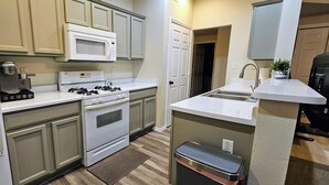 A compact kitchen with a refrigerator, microwave, stove, and sink. - Charming 3-bedroom apartment in enchanting Rio Rancho with AC, WiFi (Rio Rancho)