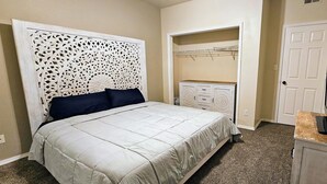 A bedroom with a bed, a TV on a stand, a wardrobe, and a walk-in closet. - Charming 3-bedroom apartment in enchanting Rio Rancho with AC, WiFi (Rio Rancho)