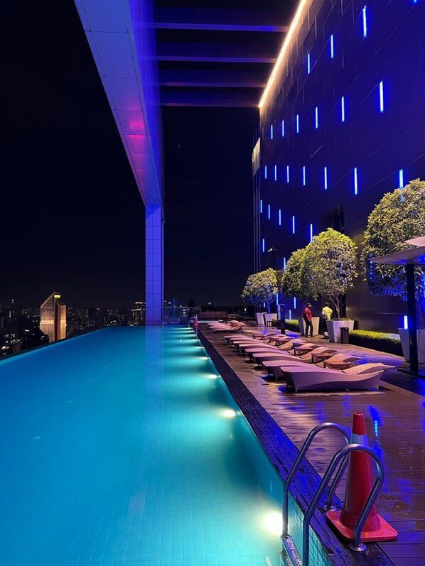 Una piscina al aire libre, sombrillas, sillones reclinables de piscina