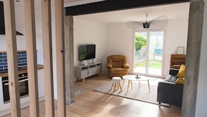 A modern living room with a TV, a sofa, a chair, and a piano. - Large, bright, quiet house with piano and sunny enclosed garden. (Guilvinec)