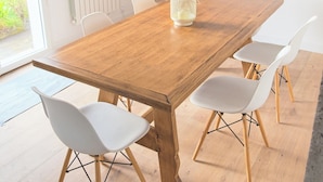 A wooden dining table with white chairs, a ladder, and pendant lights in a bright room with a radiator and a view of greenery outside. - Large, bright, quiet house with piano and sunny enclosed garden. (Guilvinec)