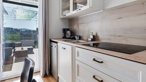 Une cuisine moderne avec des meubles blancs, un plan de travail en bois et un lave-vaisselle encastré.