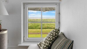 A room with a large window offering a view of a grassy field and a clear sky. - "Casjen" - 250m from the sea by Interhome (Bogense)