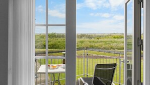 A balcony with a table and a chair, overlooking a grassy landscape. - "Casjen" - 250m from the sea by Interhome (Bogense)