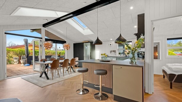 A modern kitchen with a central island, pendant lighting, and a view of the outdoors.