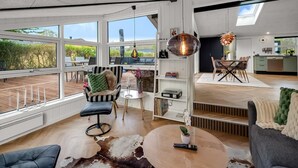 A spacious living area with large windows, a dining area, and a kitchen.